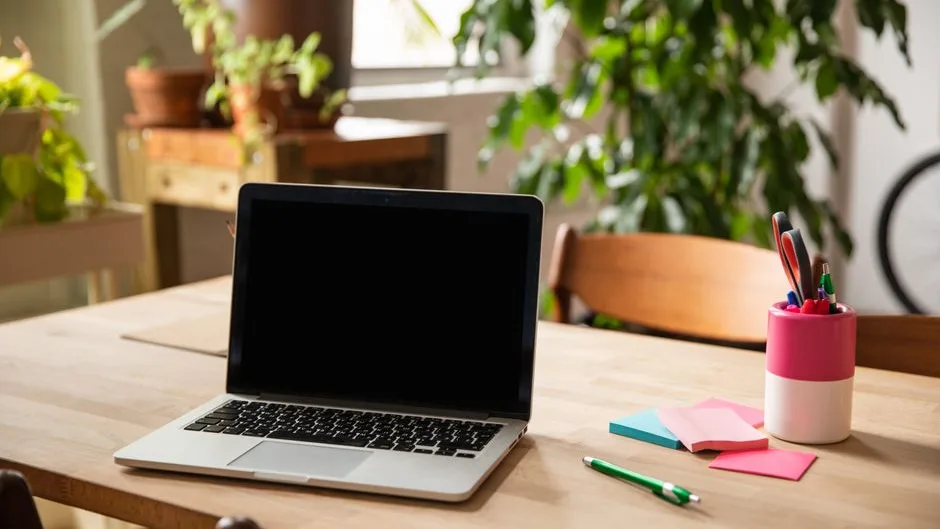 Bureau lumineux avec ordinateur portable, carnets et plantes vertes